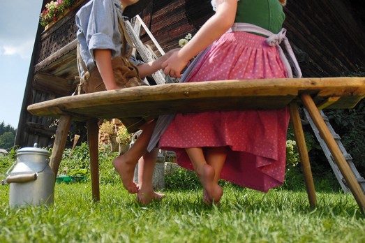 Almgebiet Ramsau am Dachstein | Mädchen und Bursch sitzen auf einer Bank auf der Almhütte